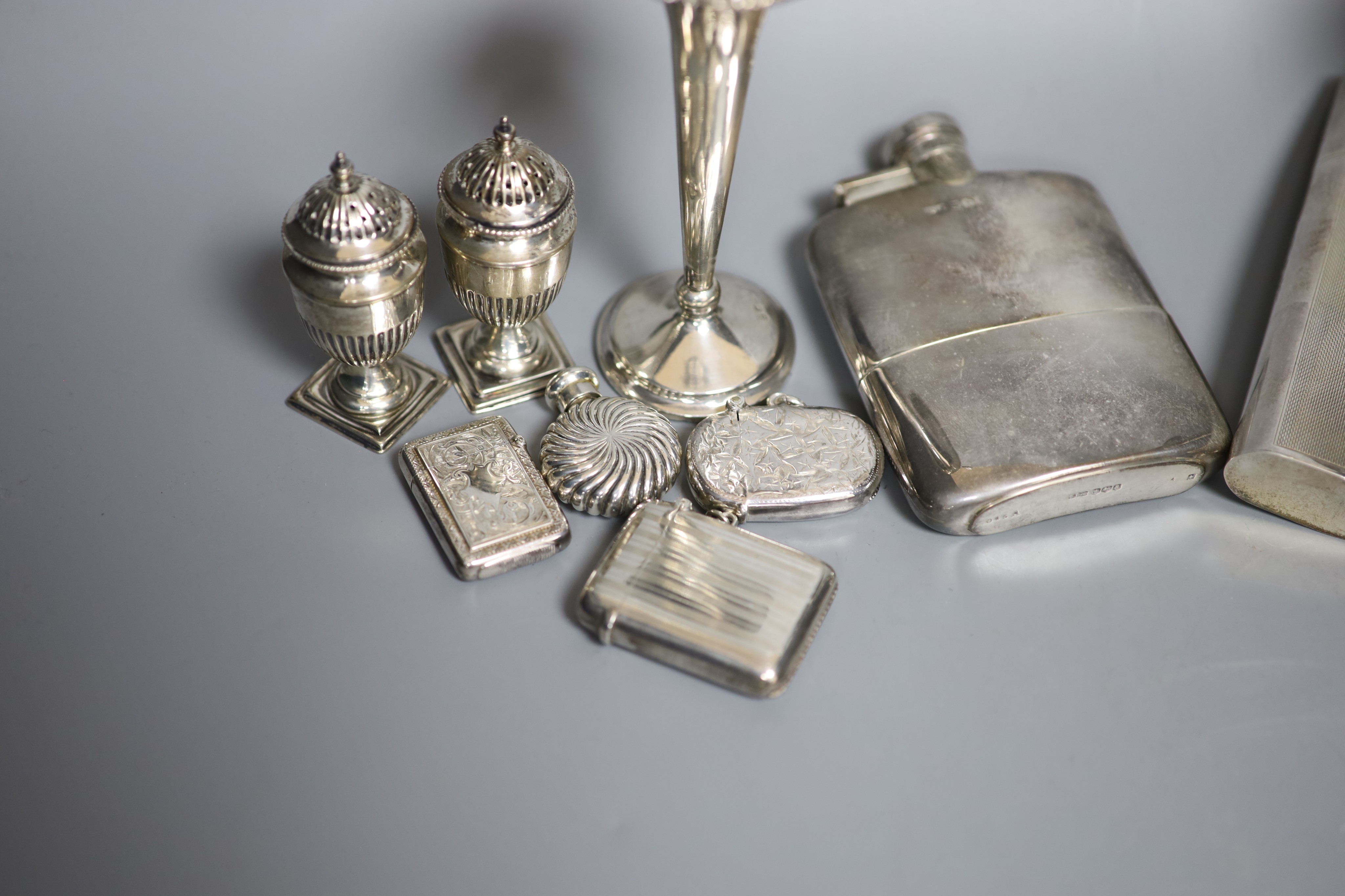 A group of assorted silver including two hip flasks, two spill vases, condiments, vesta cases, cigarette case, scent flask etc.